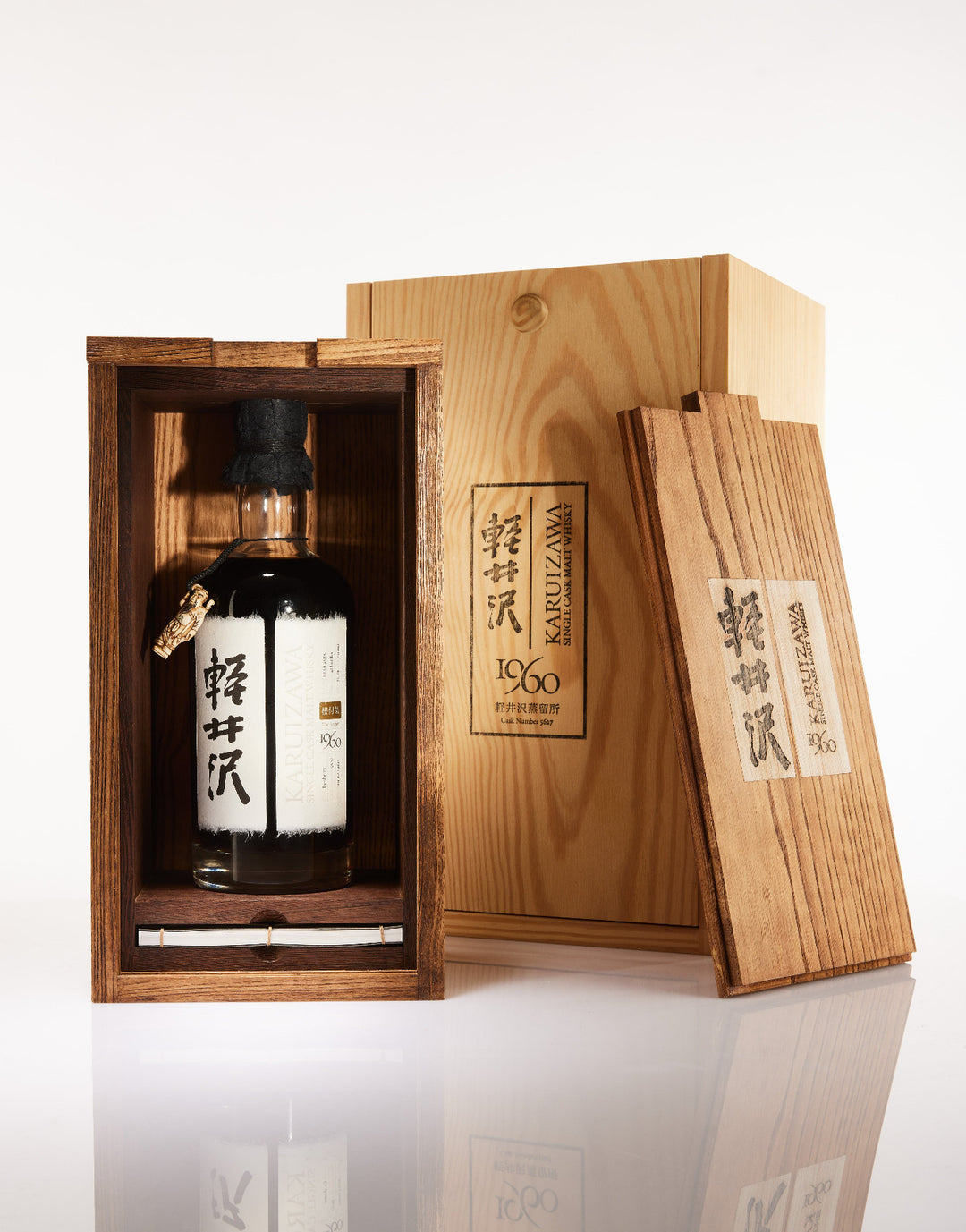 Bottle of Japanese whisky in a wooden box with intricate carvings on a white background