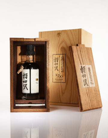 Bottle of Japanese whisky in a wooden box with intricate carvings on a white background